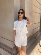 a lady wears a white short sleeve jacket with a white skirt
